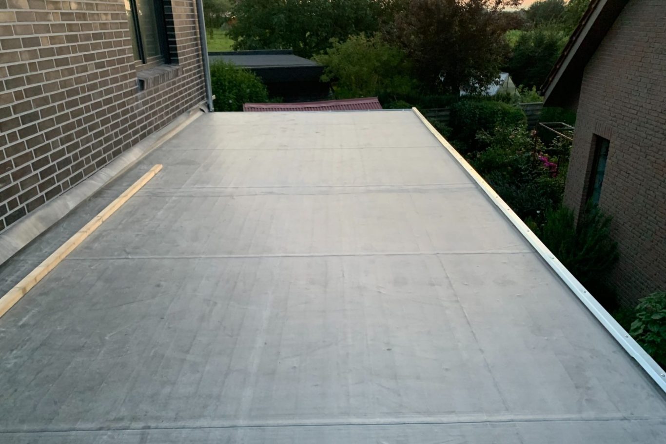 Flachdach Dachfläche mit Betonbelag, umgeben von Häusern